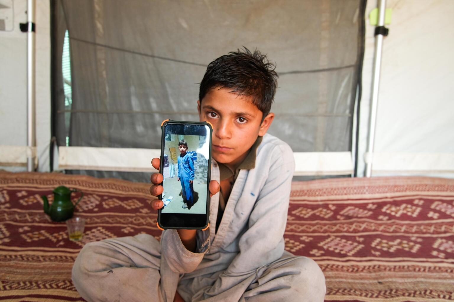 携帯電話に写る弟ハイダルの写真を見せるサルマン（アフガニスタン、2022年12月13日撮影）