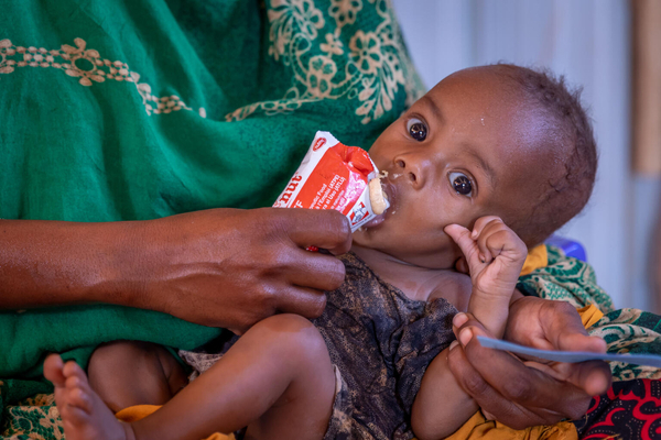 干ばつの影響により国内避難民キャンプへ逃れ、すぐに食べられる栄養治療食を母親に食べさせてもらう子ども。(エチオピア、2023年3月撮影)