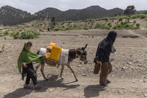 ホースト州の村に流れている川に、おばあさんと一緒にロバを連れて水を汲みに行く6歳のヌーバラさん。夏は炎天下でも毎日2時間かけて水を汲みに行っている。(アフガニスタン、2023年6月13日撮影)