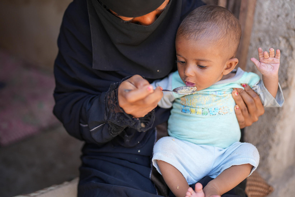 ラヒジュ県にある自宅で、母親にご飯を食べさせてもらう生後7カ月のサナドちゃん。重度の急性栄養不良のため2カ月間治療を受け、今は回復傾向にある。(イエメン、2023年5月撮影)