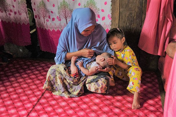 自宅で、生後11カ月の赤ちゃんに授乳する母親。(フィリピン、2023年1月撮影)