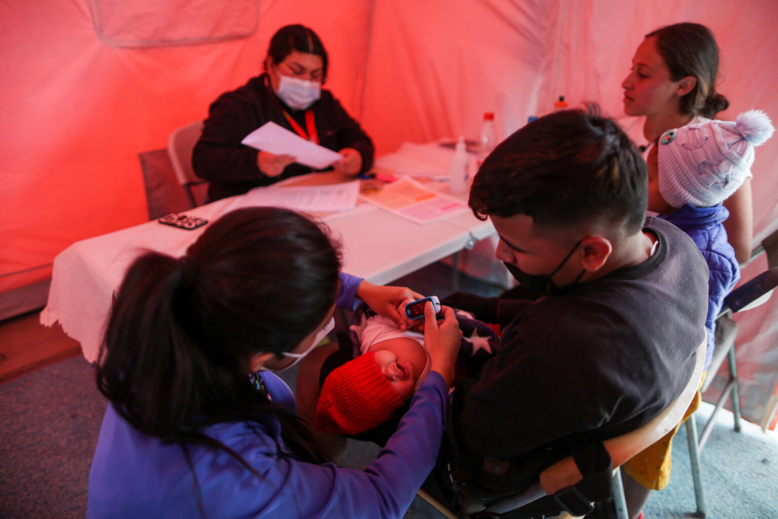 一時受け入れセンターで、ホナス（4歳）とダミアン（生後1カ月半）が、医療従事者による診察を受けている。（チリ、2022年4月27日撮影）