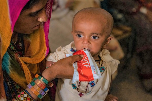 すぐに食べられる栄養治療食(RUTF)を母親に食べさせてもらう重度の急性栄養不良の1歳のラシードちゃん。(パキスタン、2023年6月撮影)