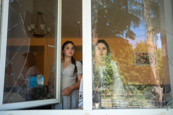 戦闘により破壊された学校のひびが入った窓から外を見るソフィアさん(17、左)とバレリアさん(16、右)。(ウクライナ、2023年6月撮影)