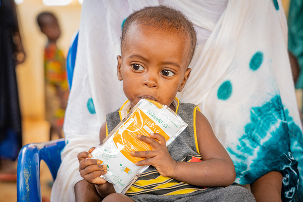 バワ国内避難民キャンプの移動式保健クリニックで、すぐに食べられる栄養治療食を口にする1歳のアブデルラハマンちゃん。クリニックでは、国内避難民のために予防接種や栄養検査、妊産婦検診、マラリア検査などの支援を提供している。(マリ、2023年8月29日撮影)