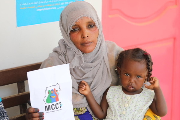 ポートスーダンの保健施設にある現金給付センターで、子どものいる家庭が四半期ごとに現金を受け取ることができる、ユニセフの現金給付プログラムに登録した親子。(スーダン、2023年7月撮影)