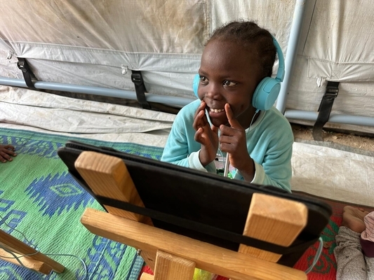 国内避難民キャンプ内のユニセフが支援する子どもにやさしい空間で、デジタル学習の支援を受ける子ども。紛争の影響を受けた子どもたちに、レクリエーション、心のケア、教育、水と衛生や保健ケアなどのサービスを提供している。(スーダン、2023年9月13日撮影)