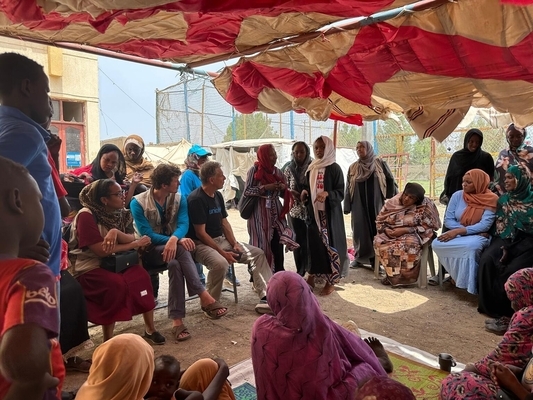 国内避難民キャンプ内のユニセフが支援する子どもにやさしい空間で、紛争で逃れてきた人たちと話すユニセフ広報官のジェームス・エルダー(中央)。(スーダン、2023年9月13日)