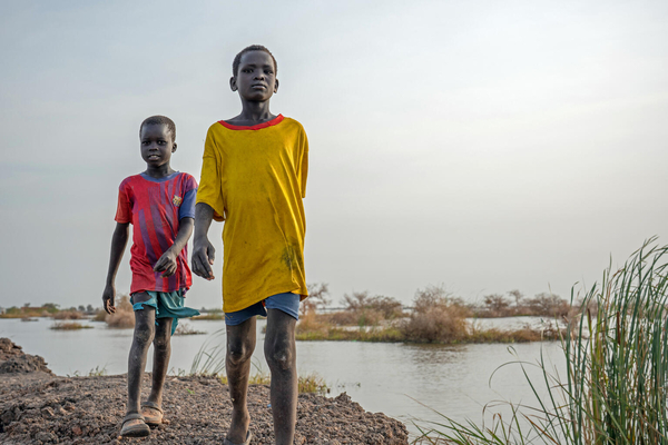 ユニティ州のベンティウで、洪水により浸水した道を歩く男の子たち。(南スーダン、2023年2月撮影)