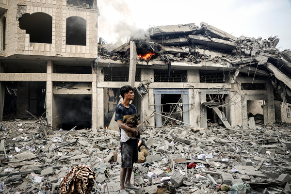 ガザ地区で、爆撃により倒壊した建物の瓦礫の上で、飼っている猫を抱きながら立ち尽くす15歳のカリムさん。(ガザ地区、2023年10月14日撮影)