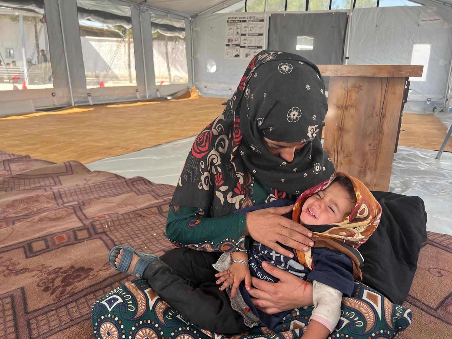 2歳の娘のアスラちゃんを抱っこしながら、ユニセフが支援する一時避難所で過ごす母親のアシファさん（アフガニスタン、2023年10月9日撮影）