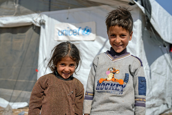 ユニセフの子どもにやさしい空間のテント前に立つ、5歳のアイシャさんと9歳のファゼルさん兄妹。(アフガニスタン、2023年10月14日撮影)