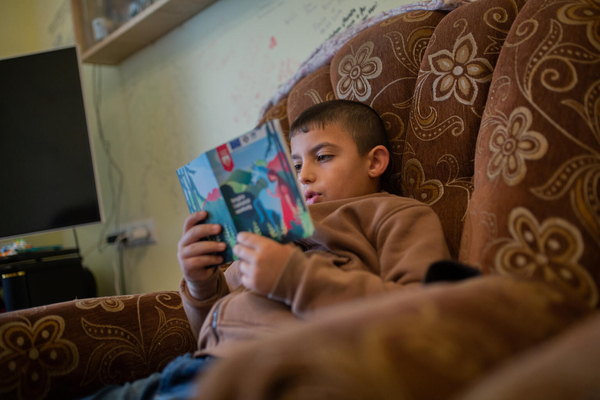祖母と3人の兄弟たちと避難し、仮住まいしている家で本を読む8歳のアルメンさん。避難途中で父親が爆発に巻き込まれ亡くなってしまった。(アルメニア、2023年10月13日撮影)