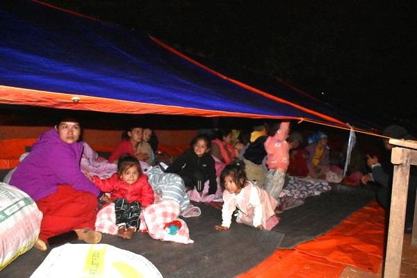 西部で発生した地震で被災し、屋外に張った防水シ－トの下で避難生活を送る家族。(ネパール、2023年11月4日撮影)