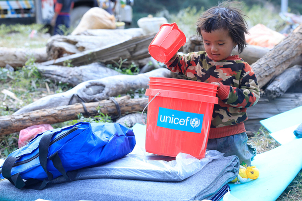 地震の被害が最も甚大だった地域のひとつ、ルクム西部のAathbiskotに届けられた、防水シートや毛布、衛生キットなどを含むユニセフの支援物資を受け取った子ども。(ネパール、2023年11月6日撮影)