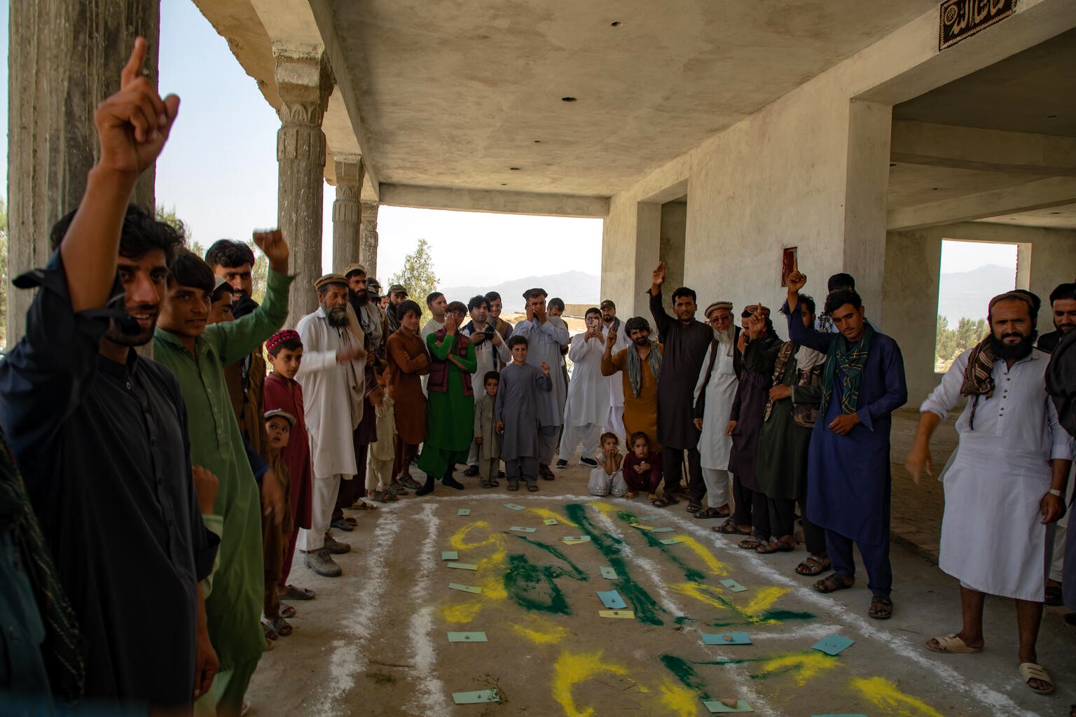 村の住民向けの研修で、足元に描かれた地図を見ながら、積極的に議論する住民たち（アフガニスタン、2023年6月19日撮影）