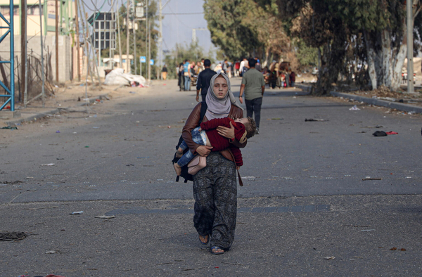 子どもを抱いて歩く女性。(ガザ地区、2023年11月26日撮影)