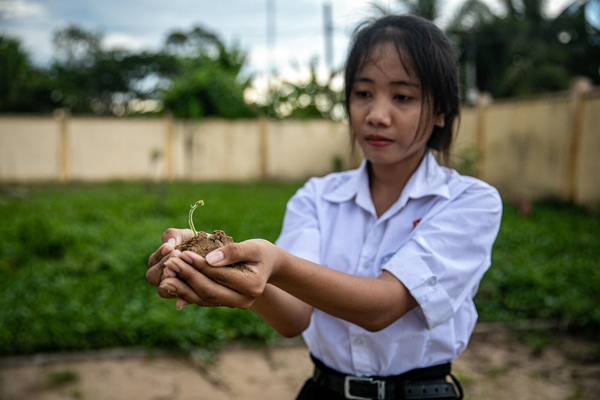 ソクチャン省の中学校で、植物の苗を手に持つ15歳のラムさん。授業で、気候変動は家族や友人にどのような影響を与えるかを学んだ。(ベトナム、2023年5月撮影)