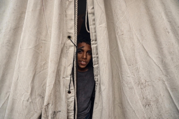 ハンユニスにある避難所のテントの中から外を見つめる11歳のカリムさん。(ガザ地区、2023年12月6日撮影)
