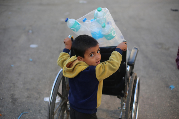 ラファで、空のペットボトルを車椅子に乗せ、水を汲める場所を探しにいくサミさん。(ガザ地区、2023年12月6日撮影)