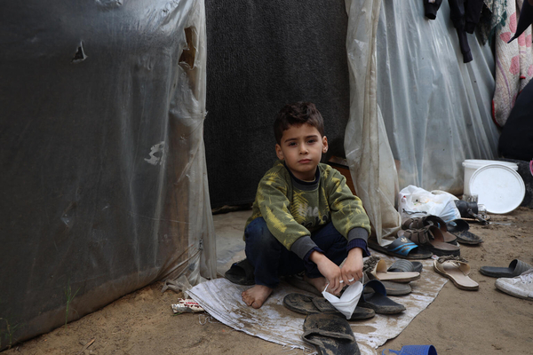 アル・アクサ大学内にある避難所のテントの隣に座り込む子ども。(ガザ地区、2024年1月11日撮影)