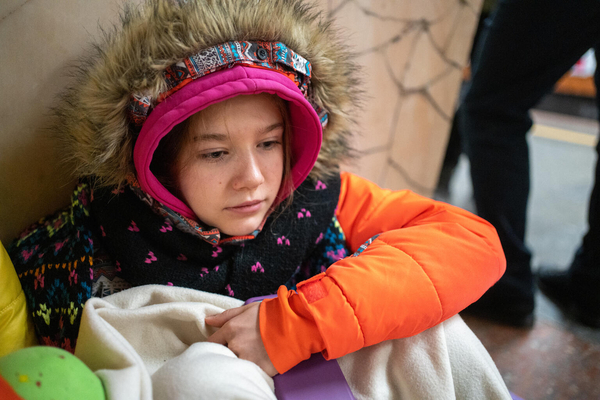 キーウの地下鉄のホームに座り込む14歳のオレクサンドラさん。3日前に爆撃を受けた隣の家の破片が自宅に直撃し、危険を感じた一家はシェルターに避難した。(ウクライナ、2024年1月2日撮影)