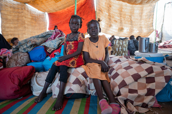ジャジャール州での戦闘激化により、2度避難を余儀なくされた10歳のエブティハルさん(右)と6歳のマブさん(左)姉妹。ワドメダニから逃れる時、勉強を続けるためにユニセフの支援で受け取ったスクールバッグを持ってきたと話す。(スーダン、2023年12月撮影)