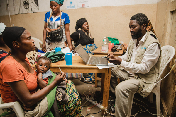 南キブ州で、ユニセフの支援物資を受け取る母親と子ども。今後3カ月間、生活に必要な食料等を買うための現金給付を受け取ることができる。(コンゴ民主共和国、2023年12月撮影)