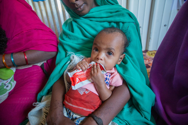 カッサラ州の保健施設で重度の栄養不良と診断され、すぐに食べられる栄養治療食を口にする2歳のアイーダちゃん。(スーダン、2024年2月29日撮影)