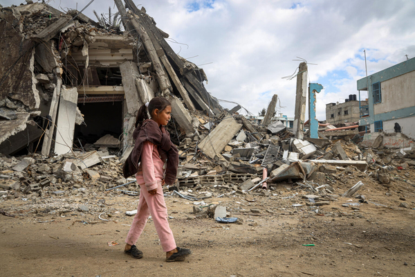 南部ハンユニスで、破壊された建物の前を歩く10歳のサマさん。 (ガザ地区、2024年3月22日撮影)