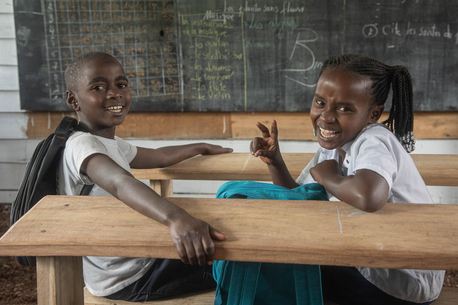 新しい教室で、隣に座って授業を受ける10歳のアムリ（左）とアディリ（右）（2024年2月4日撮影）