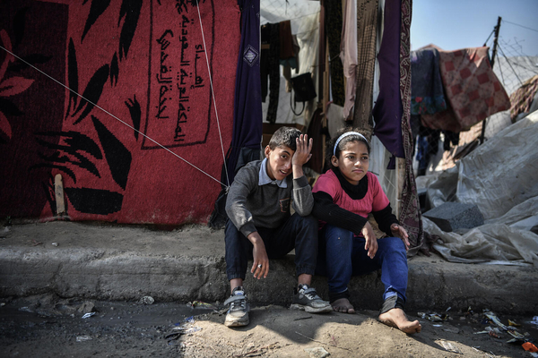 南部のラファでテント前に座る11歳のムハンマドさん(左)と12歳のハラさん姉弟。水や食料を得るために毎日長時間列に並んでいるので、疲れが見える。(ガザ地区、2024年2月撮影)