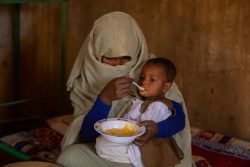 生後9カ月のムハメドちゃんに栄養価の高い食事を食べさせる母親。ユニセフが支援する母親支援のイニシアティブを通じて、食事の与え方や家庭で簡単に手に入る食材を使った栄養バランスの取れた調理方法などを学んだ。(スーダン、2024年2月撮影)