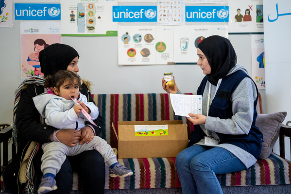ユニセフのスタッフから、2歳の娘のアシールちゃんに必要な微量栄養素についての説明を受ける母親。ユニセフは、南部での戦闘激化により避難した家族や子どもたちの栄養状態を守る支援を行っている。(レバノン、2024年2月撮影)