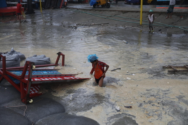 サイクロンで水没した道を渡る子ども。ユニセフはサイクロン到来以前から、命を守る支援物資をすぐに届けられるよう準備をしており、被害が大きい地域に素早くスタッフを派遣できるよう待機させていた。(バングラデシュ、2024年5月26日撮影)