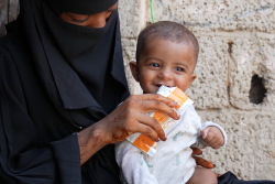 ユニセフが支援する栄養治療食を口にする子ども(イエメン、2025年3月撮影)