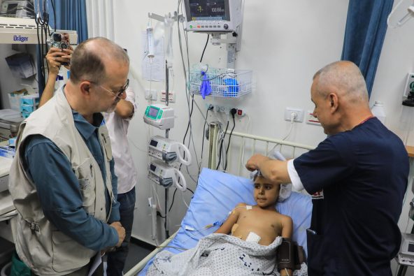 ガザ地区にある病院の集中治療室で、治療を受ける10歳の子ども（写真中央）とユニセフのテッド・チャイバン事務局次長（写真左）（パレスチナ、2025年7月29日撮影）