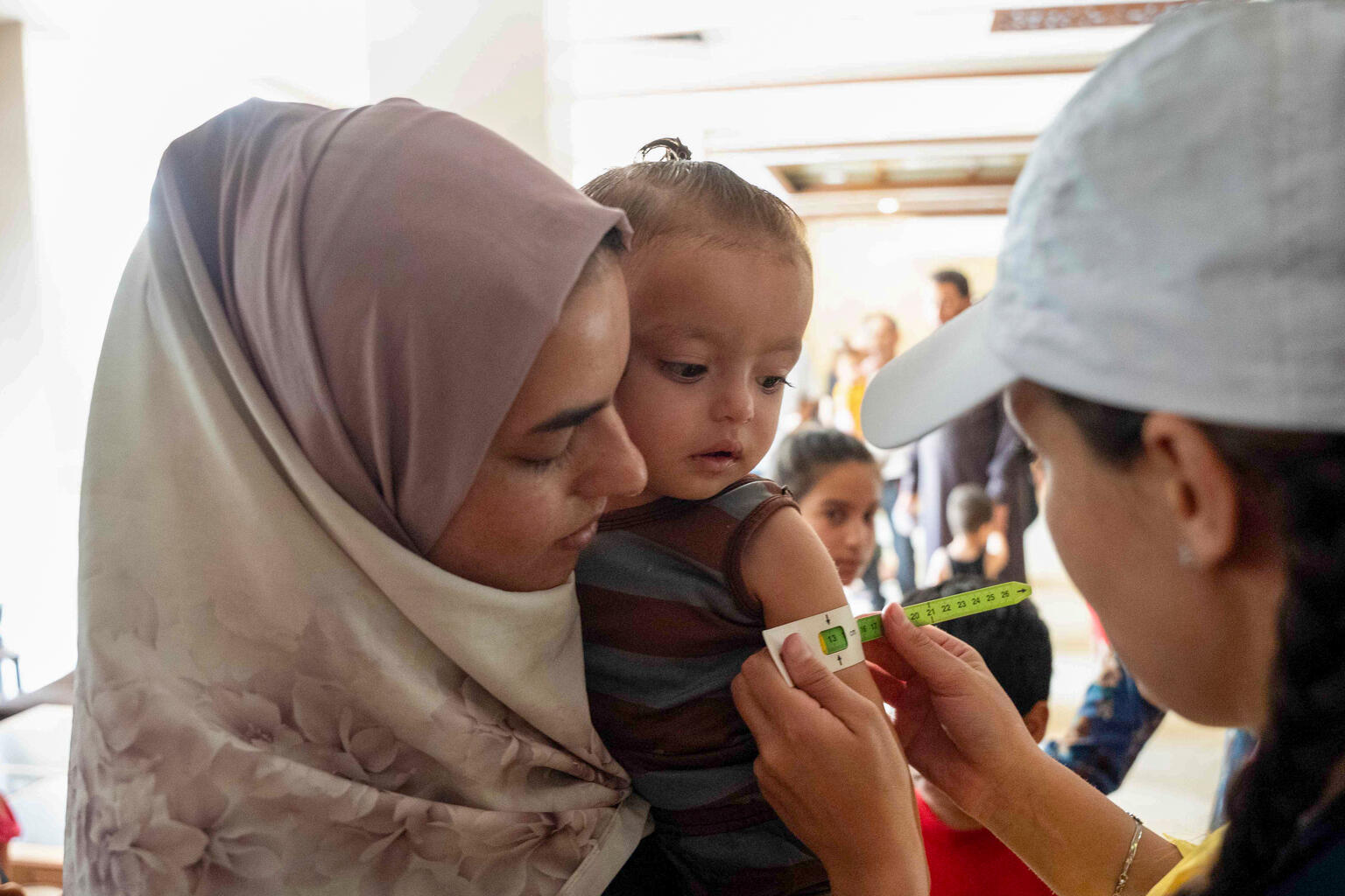 ダマスカス郊外のサイイダ・ザイナブにある避難所で、ユニセフが支援する移動式保健・栄養チームの栄養士によって栄養状態の検査を受ける3歳の子ども（シリア、2025年7月30日撮影）