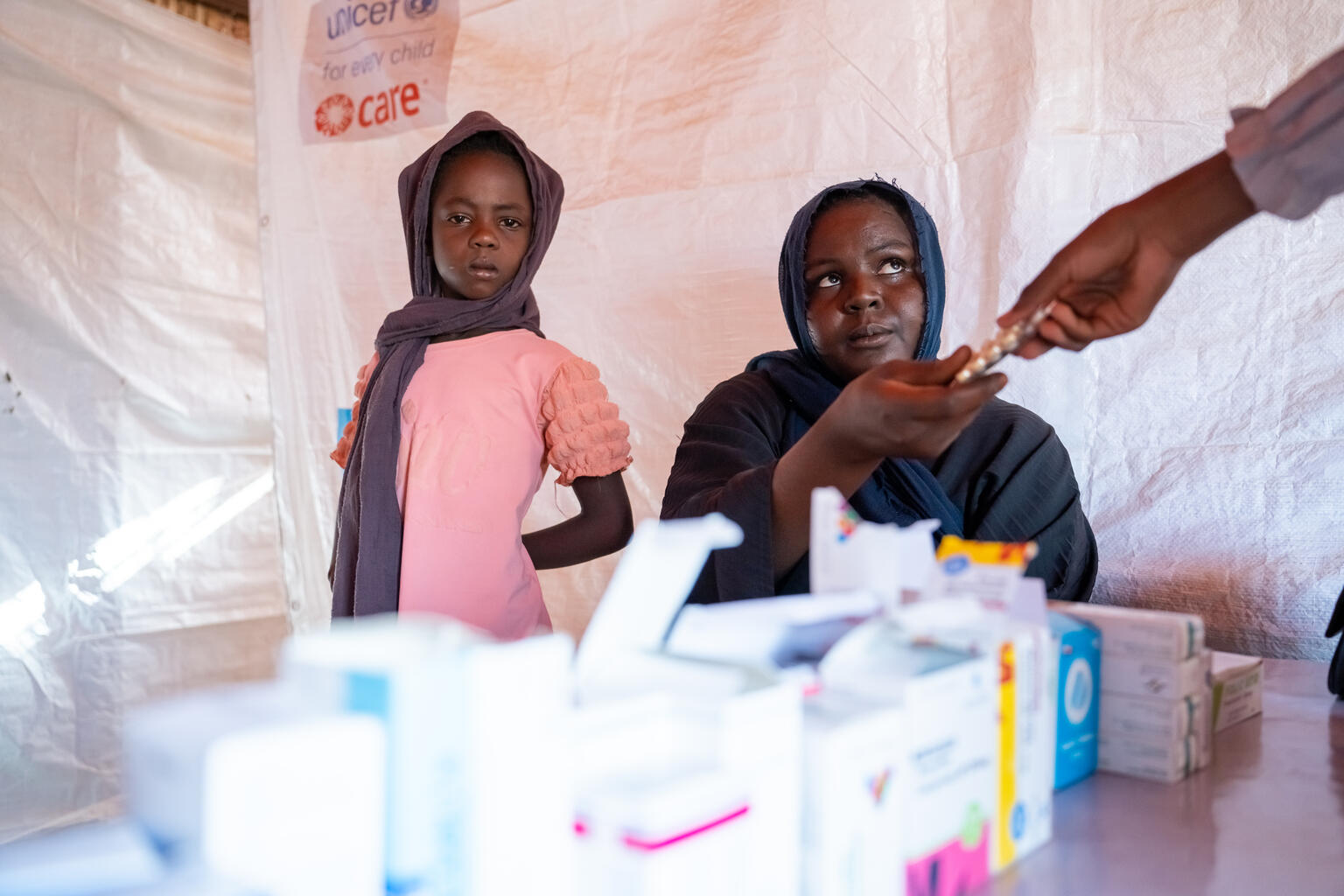 テンジルさんに処方された抗マラリア薬を受け取る母親のアミナさん（スーダン、2025年5月30日撮影）