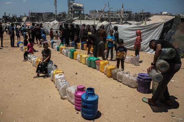 深刻な水不足が続くガザ地区の難民キャンプで、給水車の到着を辛抱強く待っている家族の様子(パレスチナ、2025年8月11日撮影)