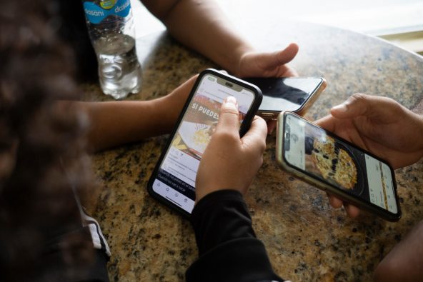 バニにあるカフェで、ファストフードのデジタル広告を見る10代の若者たち（ドミニカ共和国、2023年6月19日撮影）