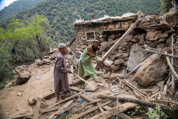 マグニチュード6.0の強い地震により倒壊したクナール県の自宅を、父親と片付ける11歳のサージェドさん(アフガニスタン、2025年9月3日撮影)