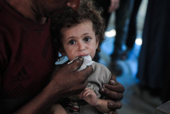 ユニセフ支援物資の栄養治療食を口にする子ども。ガザ地区では、5歳未満の全ての子どもが、栄養不良の危険にさらされている(パレスチナ、2025年8月26日撮影)