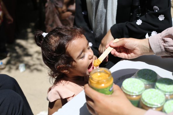 ガザ地区中部で、ユニセフ支援物資の栄養治療食を口にする子ども(パレスチナ、2025年8月7日撮影)