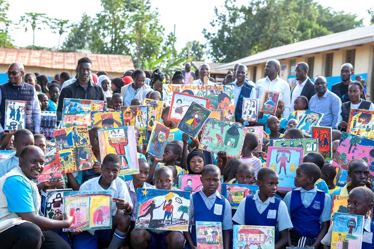 自分が描いた児童労働の根絶を訴える絵を見せる、地域の小学校の児童たち（ウガンダ、2025年6月10日撮影）