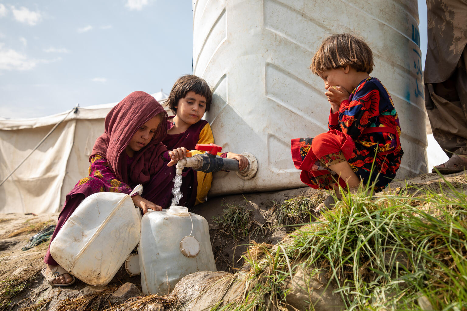 地震の被災者が暮らすSawki Zor Kali避難民キャンプで、給水設備から水をくむ7歳のハリマさん（左）（アフガニスタン、2025年9月25日撮影）