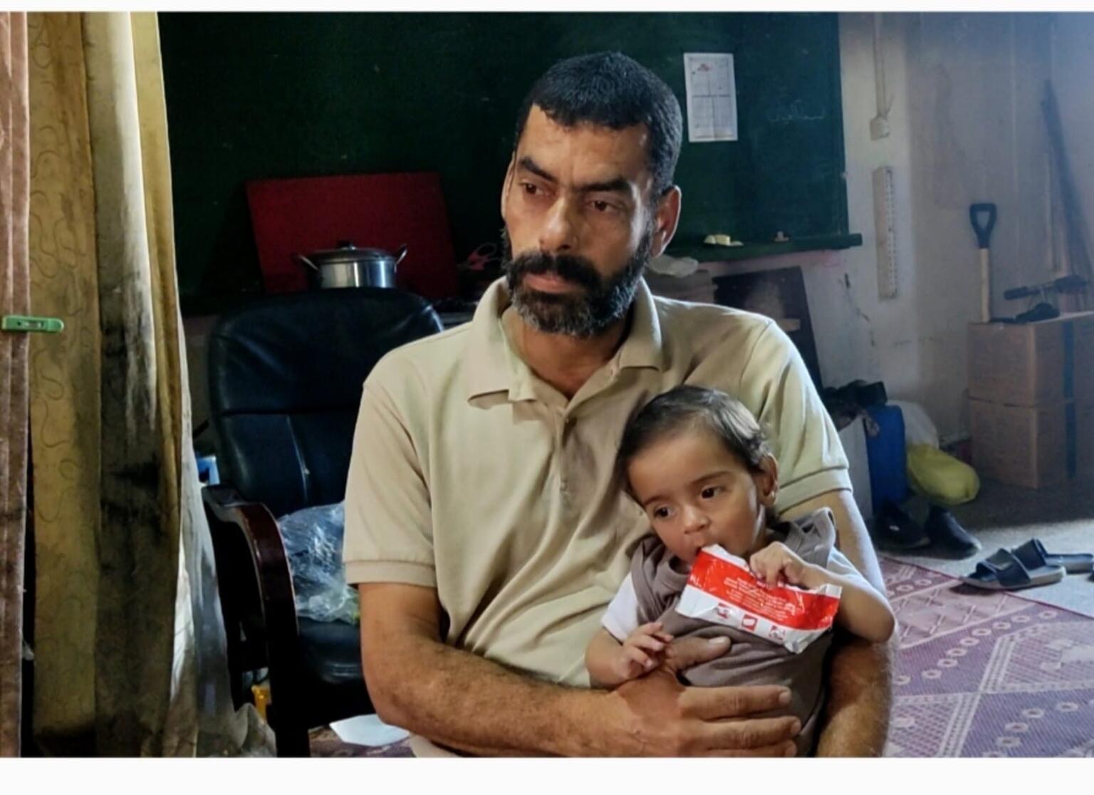 栄養治療食を口にするオデイちゃんと叔父。家族を亡くしたオデイちゃんの親代わりになっている（パレスチナ、2025年7月24日撮影）