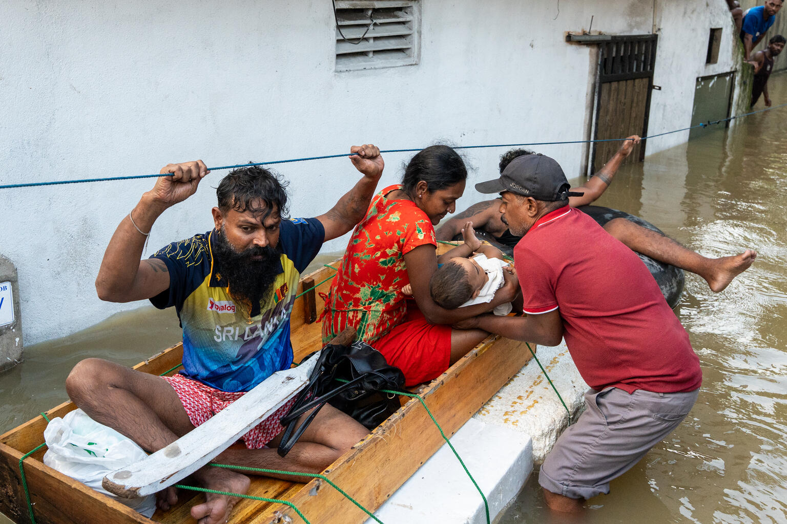 西部州ガンパハのケラニヤで、川の増水で家屋が浸水し、船により避難する家族（スリランカ、2025年11月30日撮影）