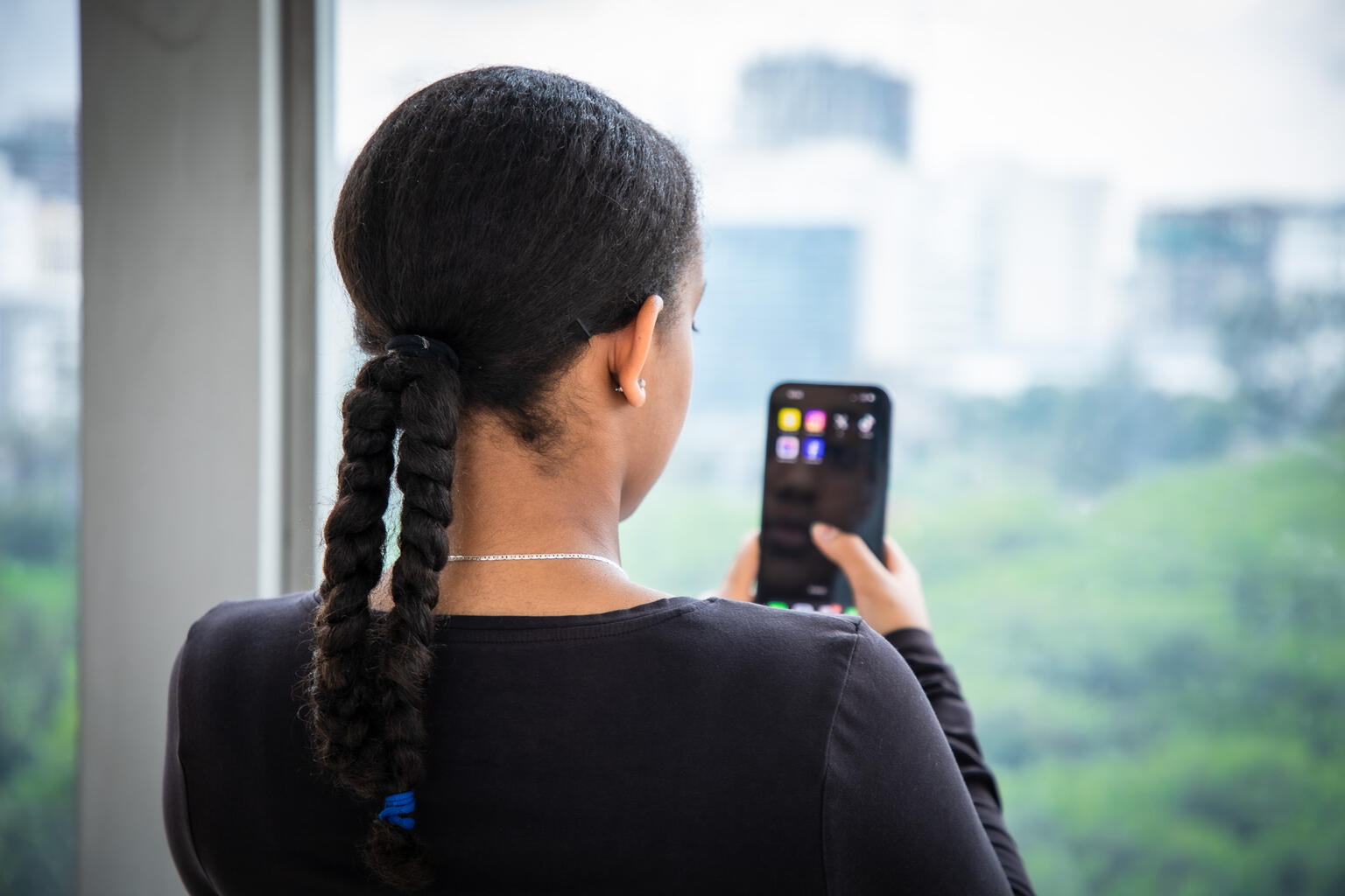 スマートフォンを操作する女の子。オンラインの世界は、無限の可能性がある一方で、いじめなどに巻き込まれるリスク等もある（エチオピア、2024年5月10日撮影）