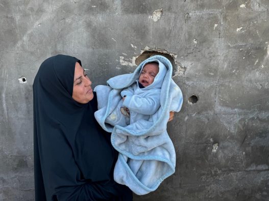 ガザ地区北部のベイト・ラヒヤにある避難民キャンプで、生後2カ月のシャディちゃんを抱くアンワルさん。厳しい寒さの中、仮設テントで暮らしている (パキスタン、2026年1月11日撮影)